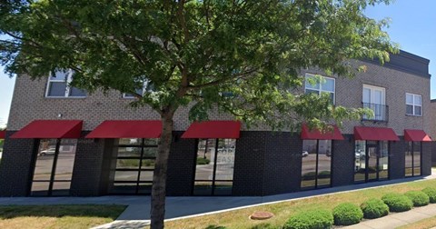 A building with red awnings and a tree in front.